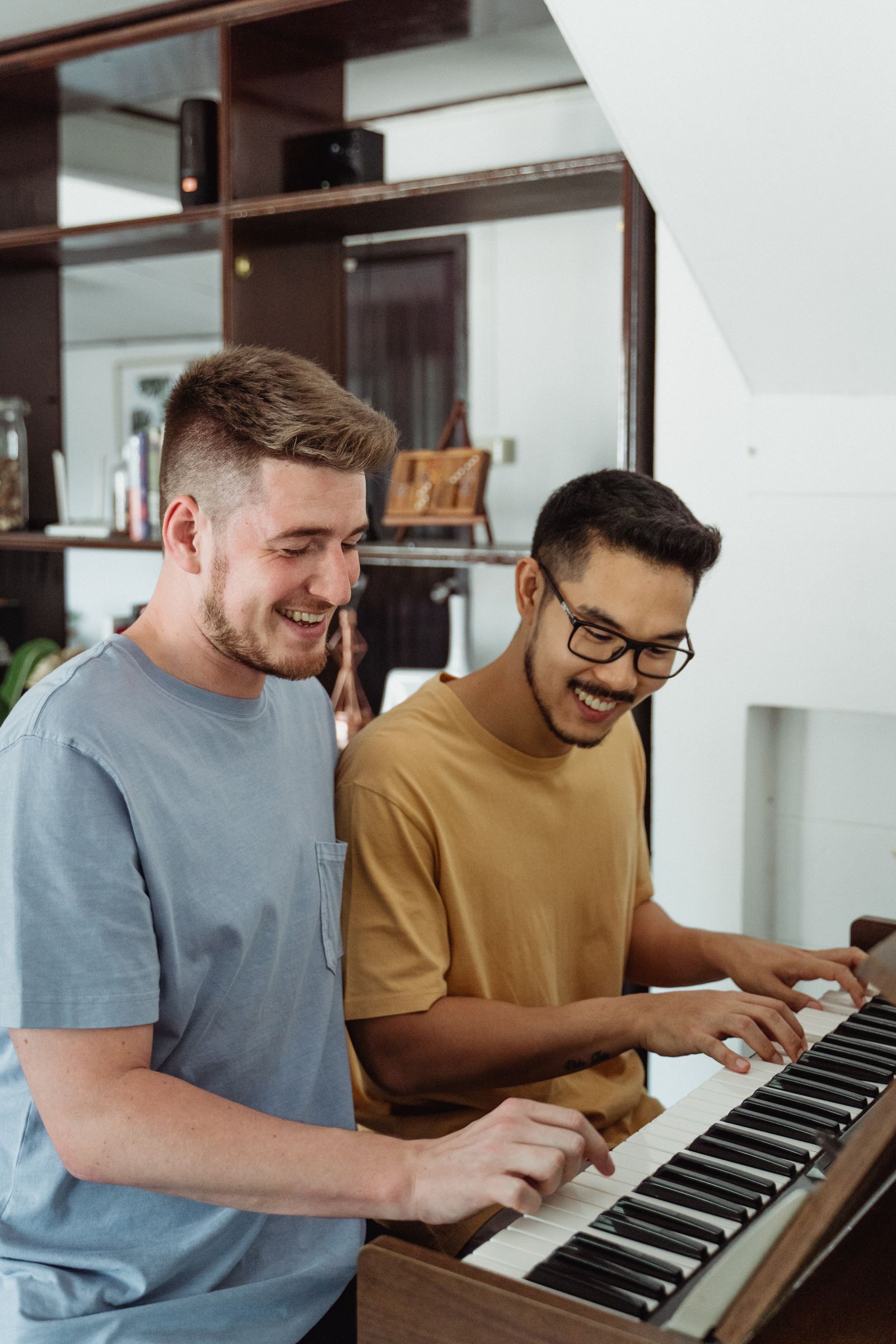 Two people sharing one piano, laughing as they play together — the shared canvas