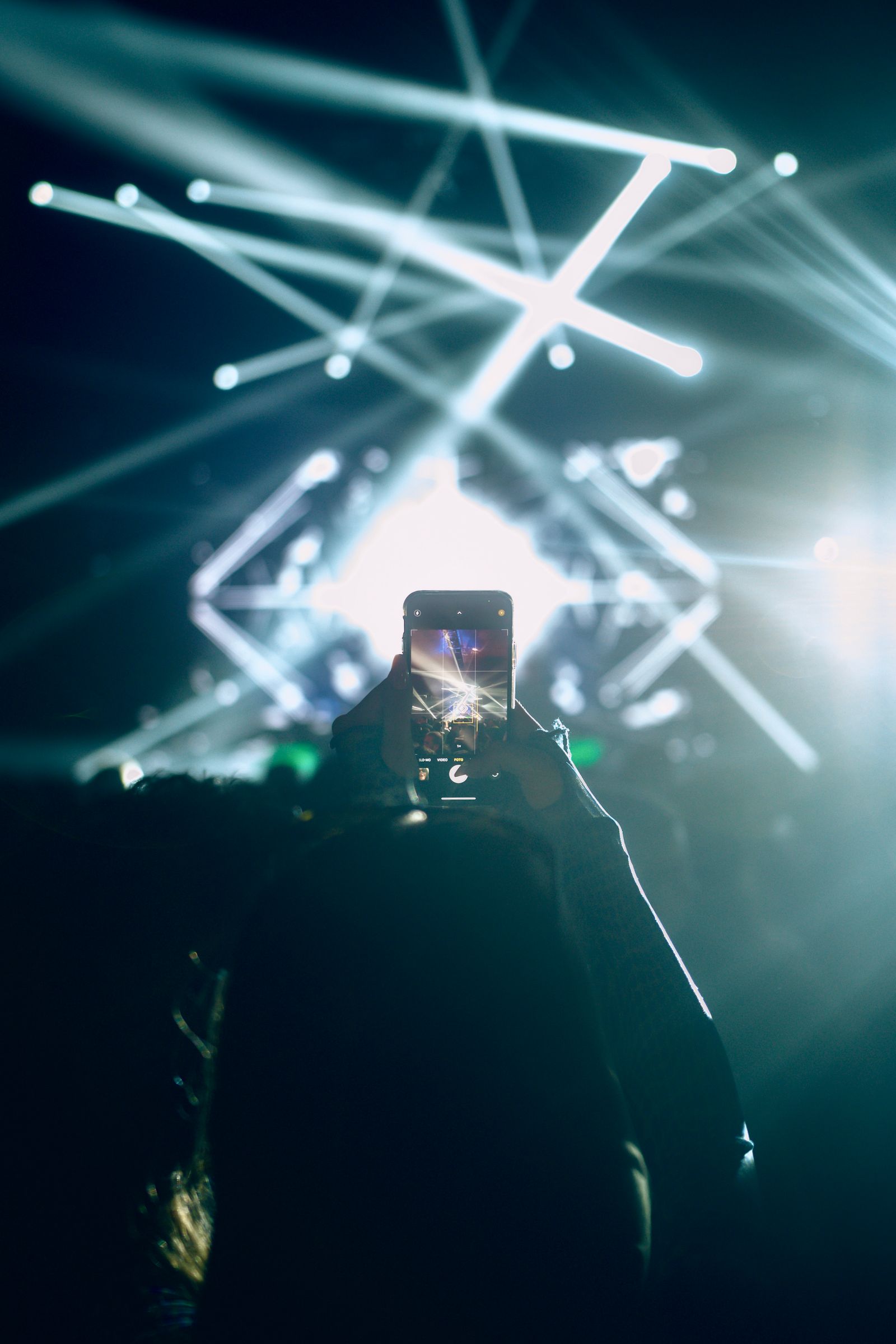The room at a championship performance — stage lights crossing while the audience records the moment