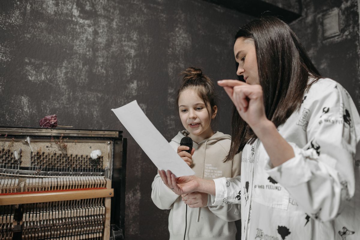 A vocal coach guiding her student through the sheet music of a song