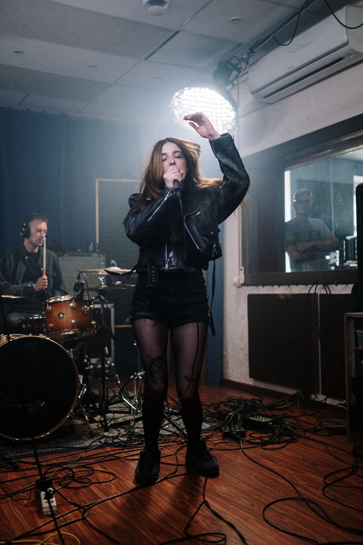A singer putting in daily practice reps in the rehearsal room, arm raised mid-note