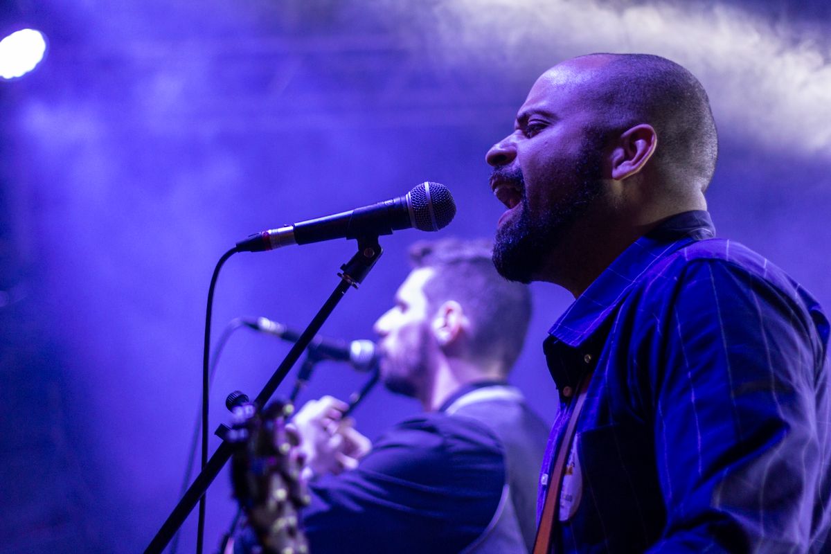 A singer performing at the microphone under purple stage lights